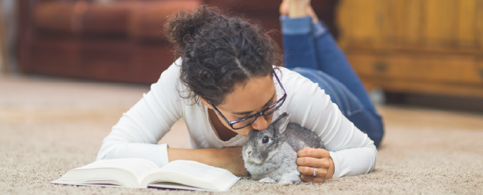 woman on floor reading with bunny